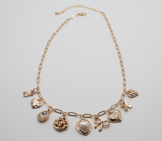  Charm Necklace.  Featuring a delicate gold-tone chain adorned with an array of feminine charms, including a pearl heart, a dainty bow, sparkling crystals, and floral motifs.