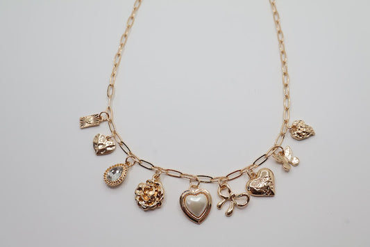  Charm Necklace.  Featuring a delicate gold-tone chain adorned with an array of feminine charms, including a pearl heart, a dainty bow, sparkling crystals, and floral motifs.