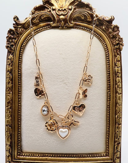  Charm Necklace.  Featuring a delicate gold-tone chain adorned with an array of feminine charms, including a pearl heart, a dainty bow, sparkling crystals, and floral motifs.
