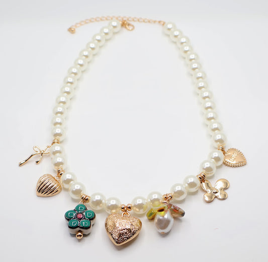 Pearl Charm Necklace is a graceful blend of timeless elegance and whimsical charm. Featuring a strand of lustrous pearls adorned with delicate gold-tone charms, including hearts, flowers, and a touch of sparkle.
