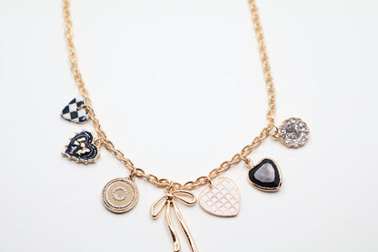  Charm Necklace is a whimsical and eye-catching accessory, perfect for adding character to any outfit. This necklace features a series of unique charms, including hearts, a bow, a sparkling gem, and intricate patterns, all beautifully arranged on a gold-tone chain.