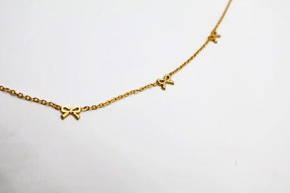  Gold Bow Charm Necklace is a delicate and timeless accessory that exudes elegance and charm. Featuring three dainty bow-shaped accents.