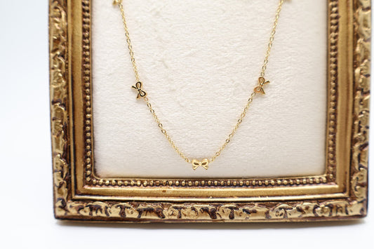 Gold Bow Charm Necklace is a delicate and timeless accessory that exudes elegance and charm. Featuring three dainty bow-shaped accents.