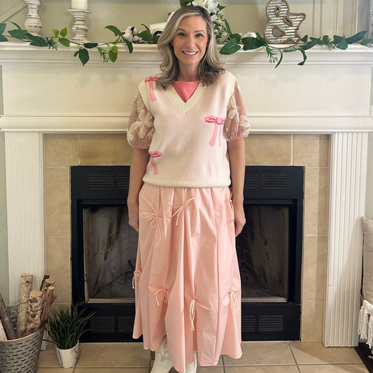 Bow Sweater Vest featuring an all-over bow design, this is a sleeveless sweater vest with a V-neckline. 