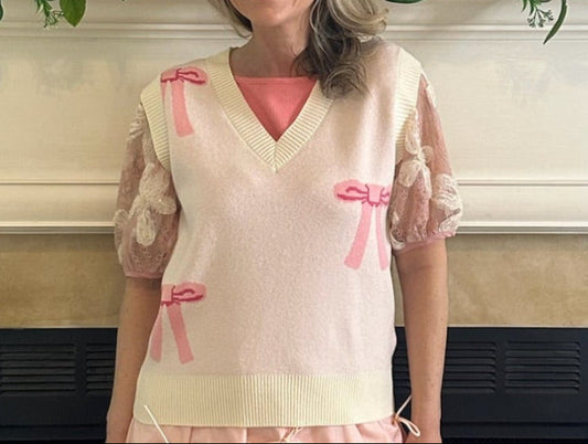 Bow Sweater Vest featuring an all-over bow design, this is a sleeveless sweater vest with a V-neckline. 