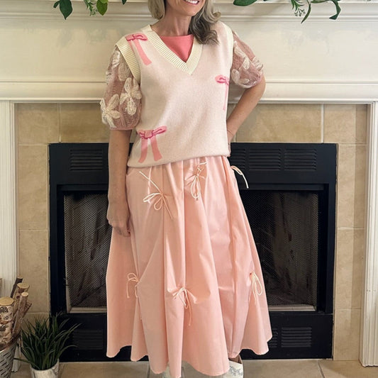Blush Pink Bow Detail Midi Skirt is a feminine and elegant piece designed to elevate your wardrobe. This flowy midi skirt features delicate bow accents throughout.