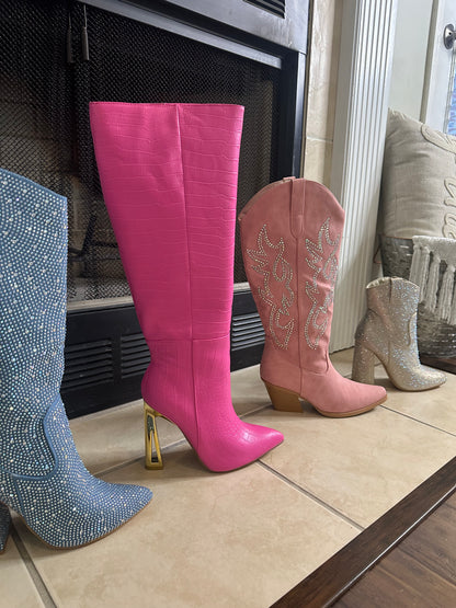  Croc Knee-High Boots are a bold statement piece designed to elevate any outfit. Featuring an eye-catching croc-embossed texture and a vibrant pink hue.
