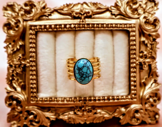 Ring embodies the essence of natural beauty and bohemian elegance. Featuring an oval turquoise stone with captivating veining, set on a layered gold-tone band.