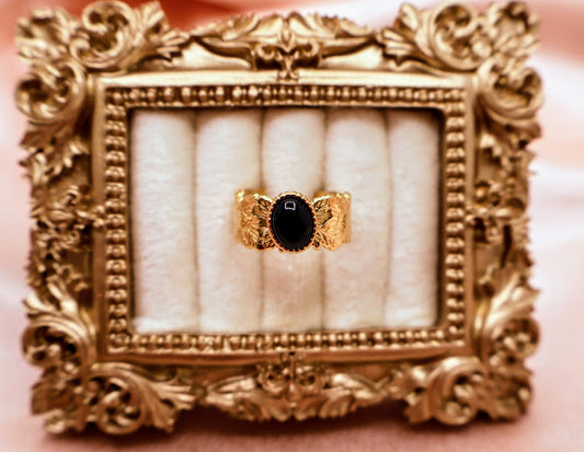  Ring is a bold yet elegant statement piece, designed for those who embrace their unique style. Featuring a striking oval black stone framed by textured gold-tone detailing.