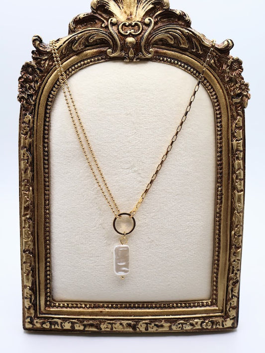  Pendant Necklace is a chic and modern accessory that embodies effortless style. Featuring a stunning rectangular pearl-like charm suspended from a sleek gold-tone ring.