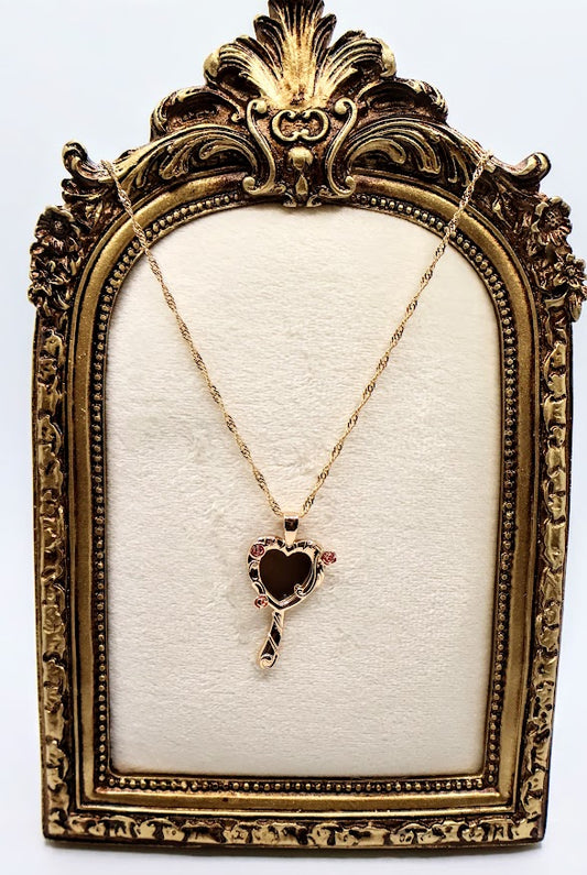  Rose Mirror Necklace is a stunning symbol of elegance and charm. The heart-shaped pendant, designed as a petite mirror, features intricate gold swirls and delicate pink rose accents that add a romantic touch.