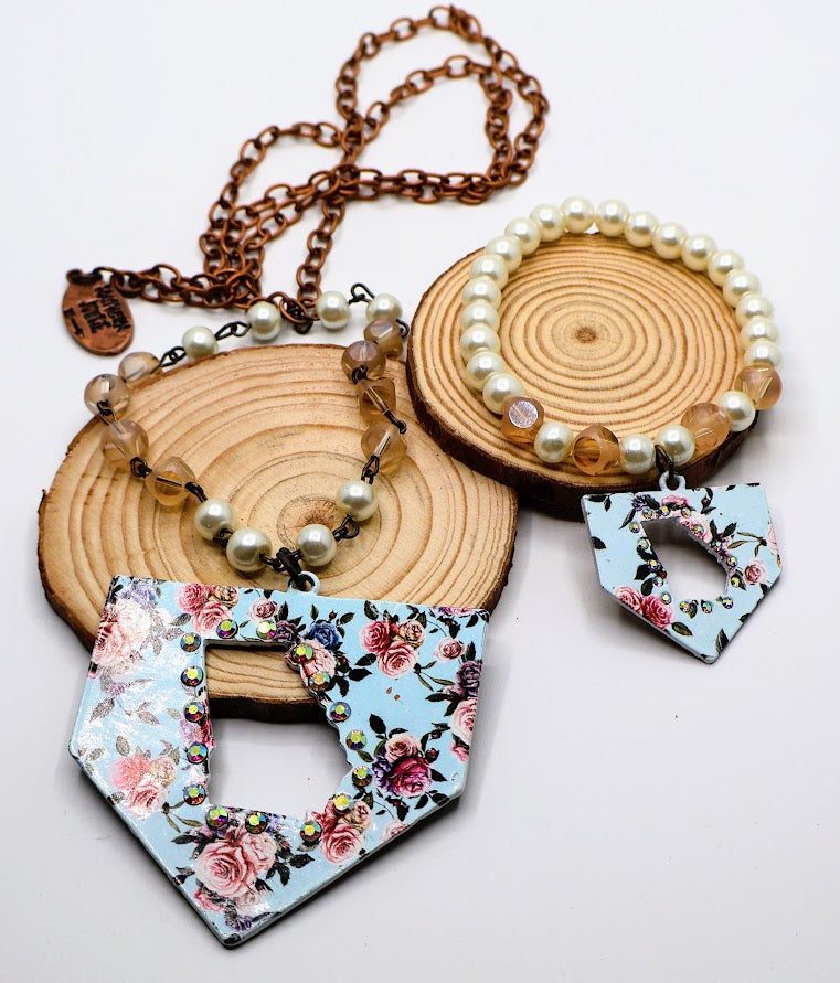 Floral pendant necklace and earrings on wooden discs with a white background