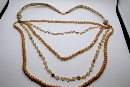 Multi-layerded Necklace featuring strands of ivory-toned beads, shimmering chains, and delicate gold accents.