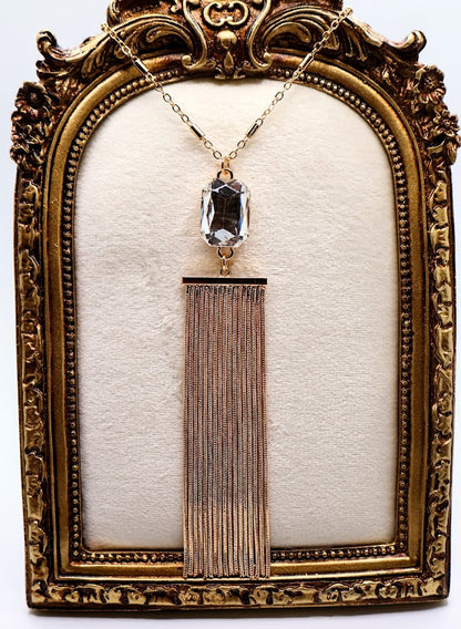 Necklace features a stunning crystal pendant that sparkles with every movement, elegantly paired with a flowing golden tassel.