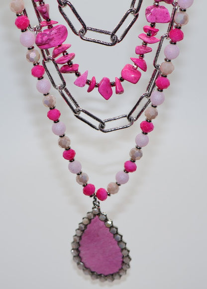 Necklace combines bold pink beads, silver chains, and a stunning teardrop pendant accented with sparkling rhinestones.