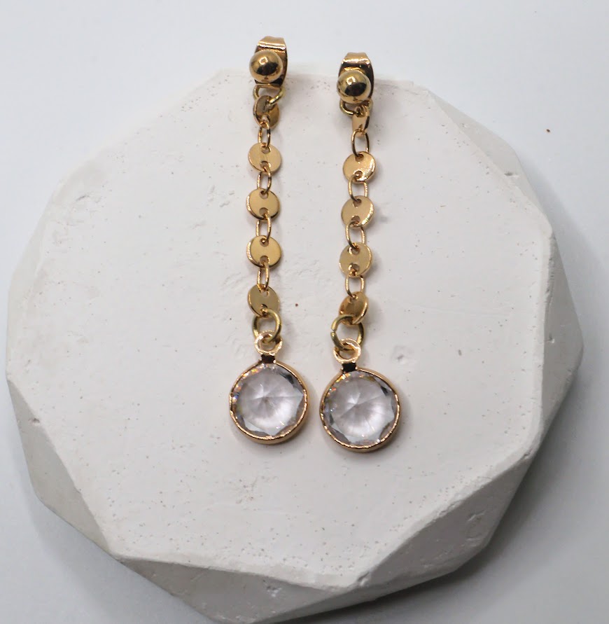 Gold earrings featuring dainty gold chains and sparkling crystal accents.