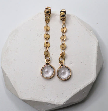 Gold earrings featuring dainty gold chains and sparkling crystal accents.