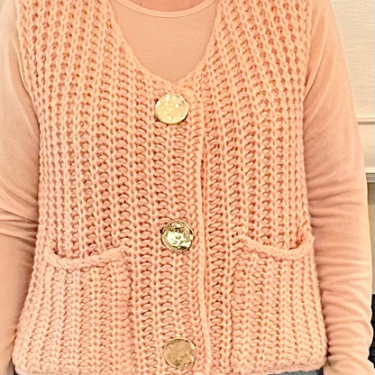 Person wearing a pink knitted vest with buttons