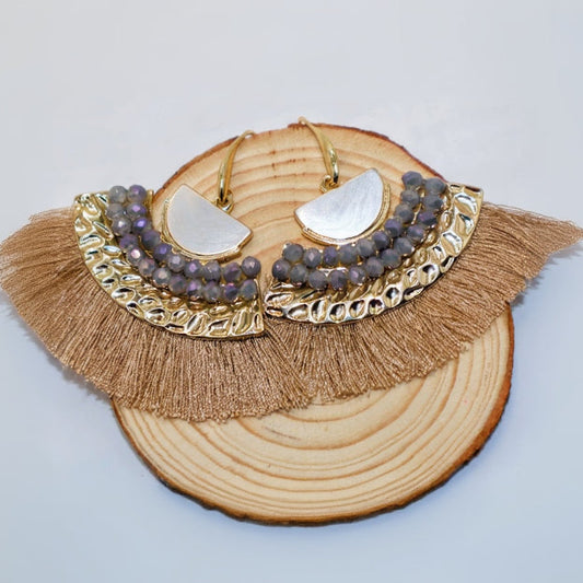 Gold-framed earrings with purple beads on a wooden block