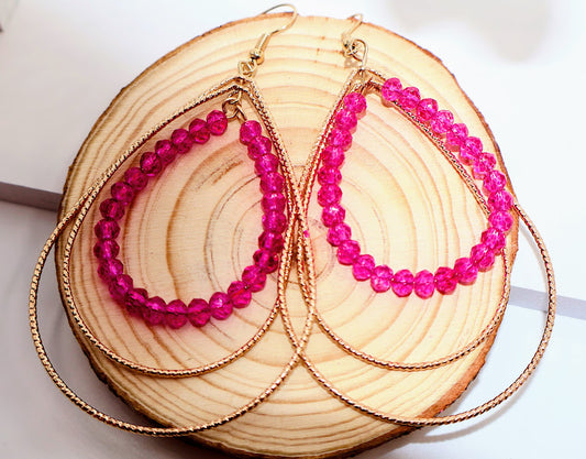 Pink beaded hoop earrings on a wooden surface