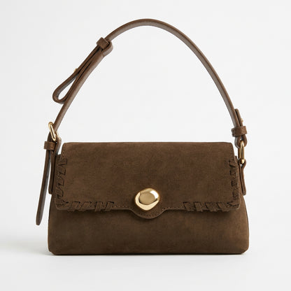 Brown flap-front shoulder bag with whipstitch edging and round gold-tone accent