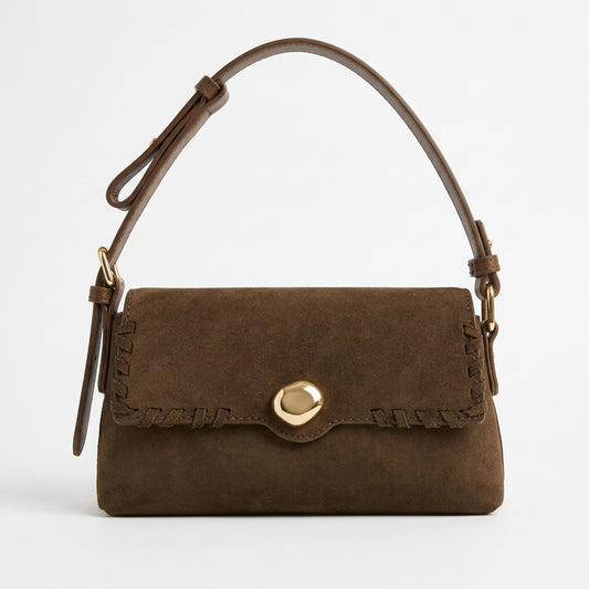 Brown flap-front shoulder bag with whipstitch edging and round gold-tone accent