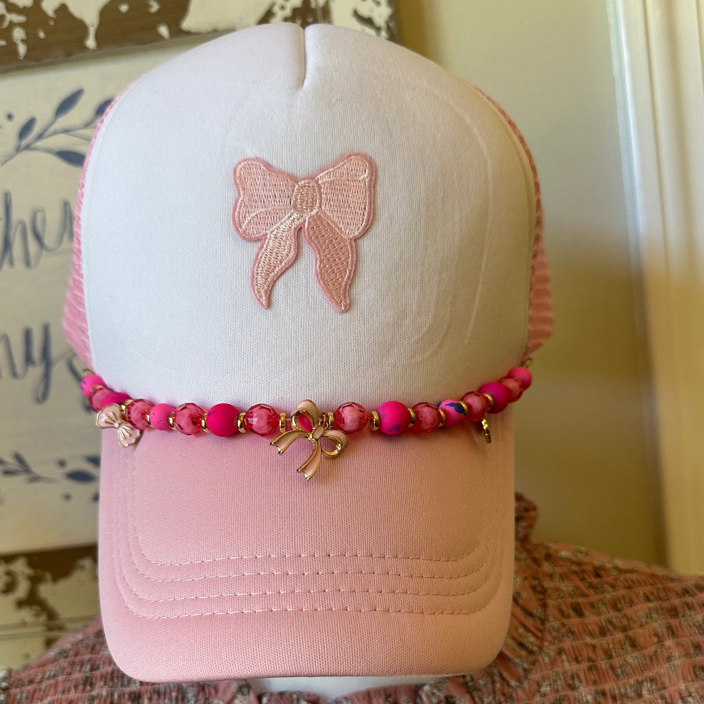 Pink cap with a bow design on a mannequin head against a neutral background