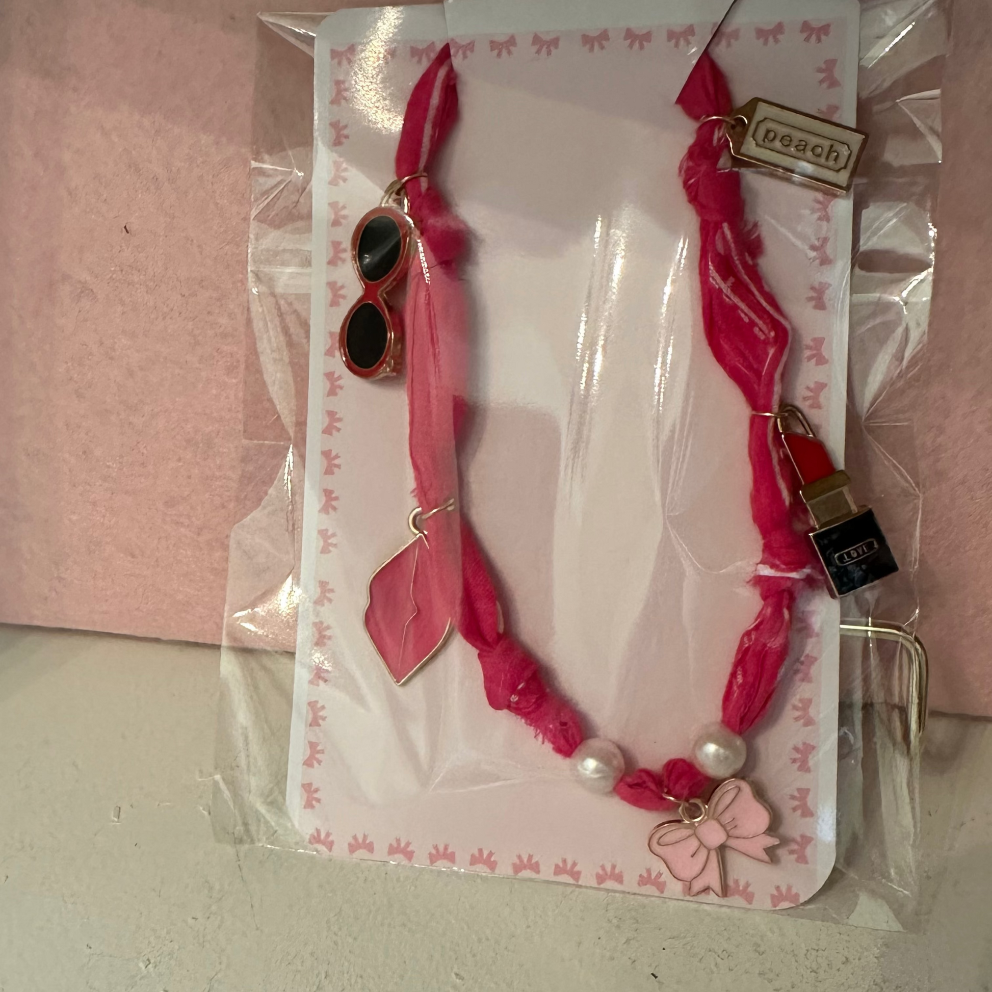 Pink choker necklace with heart pendants against a pink background