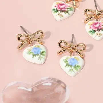 Heart-shaped earrings with floral designs on a pink background