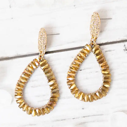 Gold teardrop earrings on a marble surface