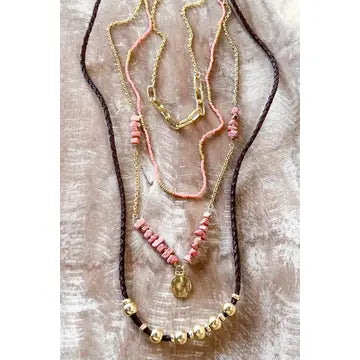 Three necklaces with beads and a pendant on a textured surface