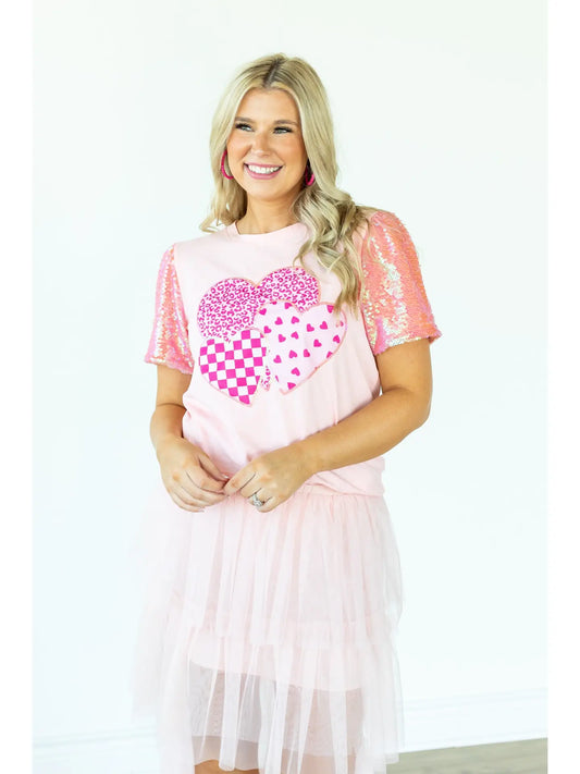 Sequin Sleeve Top is a playful and chic piece that stands out in any wardrobe. Featuring dazzling sequin-lined sleeves and a bold heart graphic.