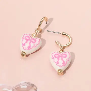 Heart-shaped earrings with pink marbled design on a pink background