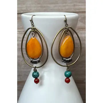 Pair of earrings with orange beads on a white stand