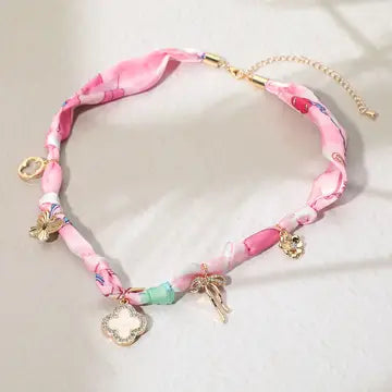 Pink ribbon choker necklace with charms on a light background