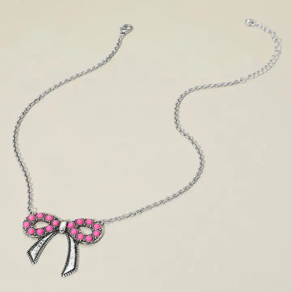 Necklace with a pink bow pendant on a beige background
