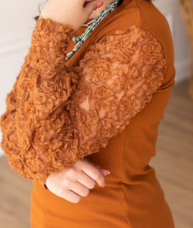 Close-up of a person wearing an orange textured sweater with blurred background