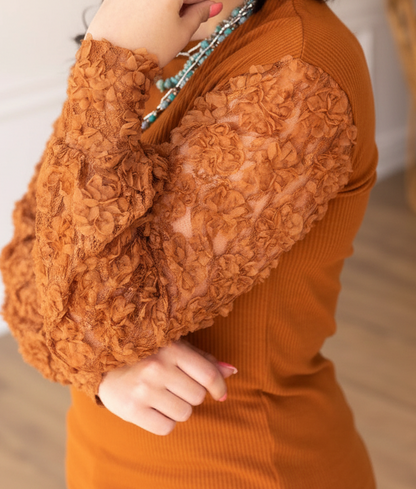 Close-up of a person wearing an orange textured sweater with blurred background