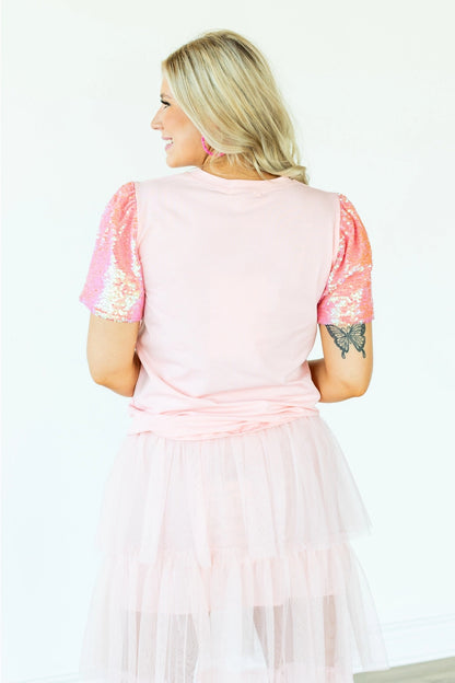 Sequin Sleeve Top is a playful and chic piece that stands out in any wardrobe. Featuring dazzling sequin-lined sleeves and a bold heart graphic.