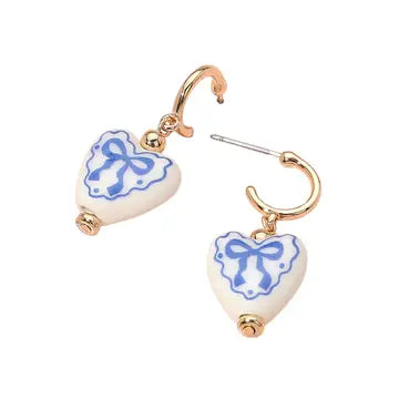 Heart-shaped earrings with blue bows on a white background
