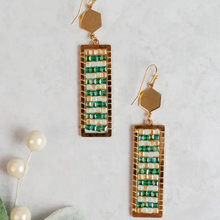 Gold and green beaded earrings on a light gray background