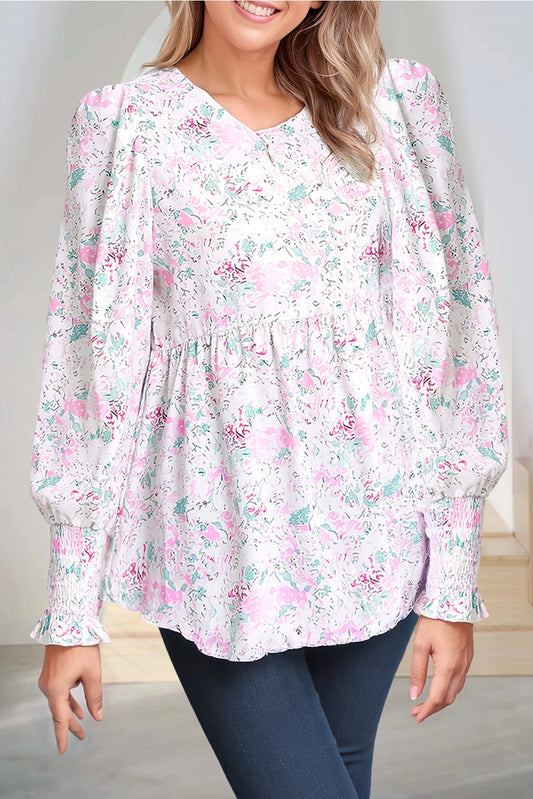 Floral Print Blouse. This blouse features a charming floral print in soft, pastel tones. The design includes a flattering V-neckline, long puffed sleeves with smocked cuffs, and a relaxed, flowy fit.