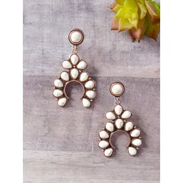 Pair of earrings with white stones on a gray surface