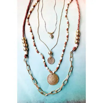 This versatile necklace features a lobster claw closure and a 2-inch extender for a customizable fit. Adorned with unique charms and pendants, including a delicate gold heart and textured gold disks