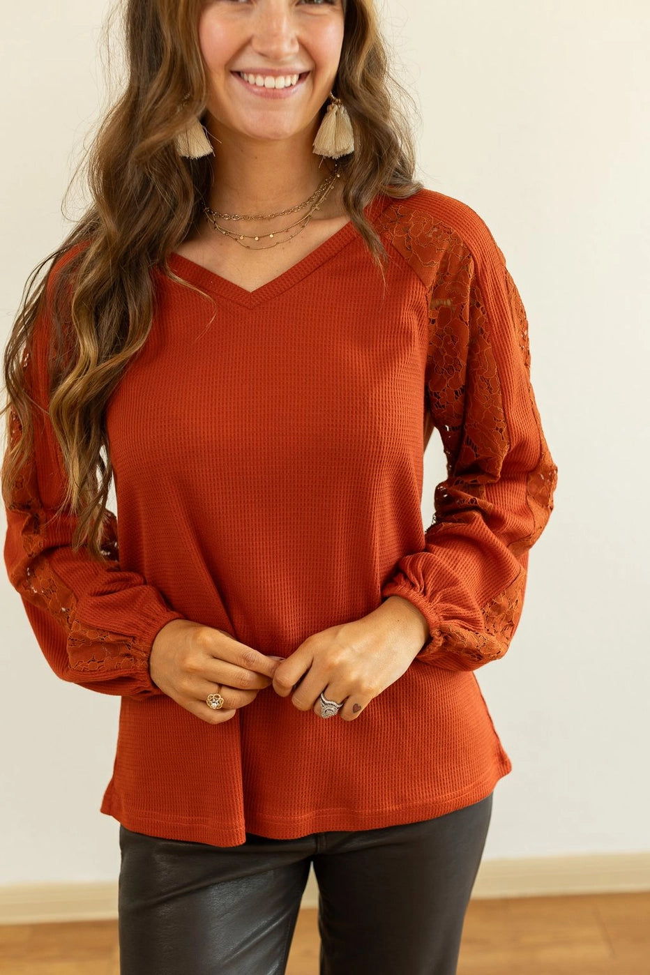 Rust Lace Sleeve V-Neck Top is a perfect balance of casual elegance and comfort. Designed with a relaxed fit and some stretch, this top features a flattering V-neckline and intricate lace inserts on the sleeves.