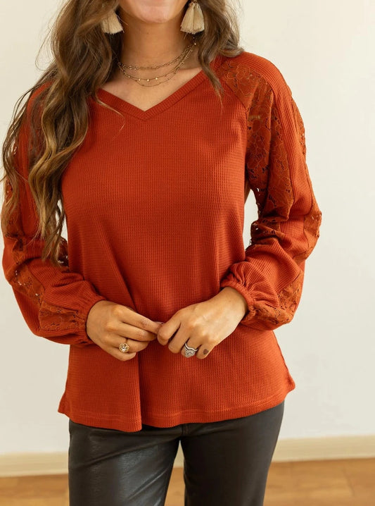 Rust Lace Sleeve V-Neck Top is a perfect balance of casual elegance and comfort. Designed with a relaxed fit and some stretch, this top features a flattering V-neckline and intricate lace inserts on the sleeves.
