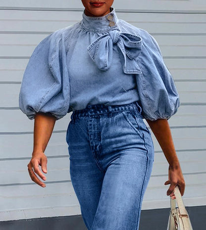  Puff Sleeve Denim Blouse is a stylish and versatile piece that combines casual comfort with a chic design. Featuring 3/4-length loose puff sleeves and a high neckline adorned with a statement bow.