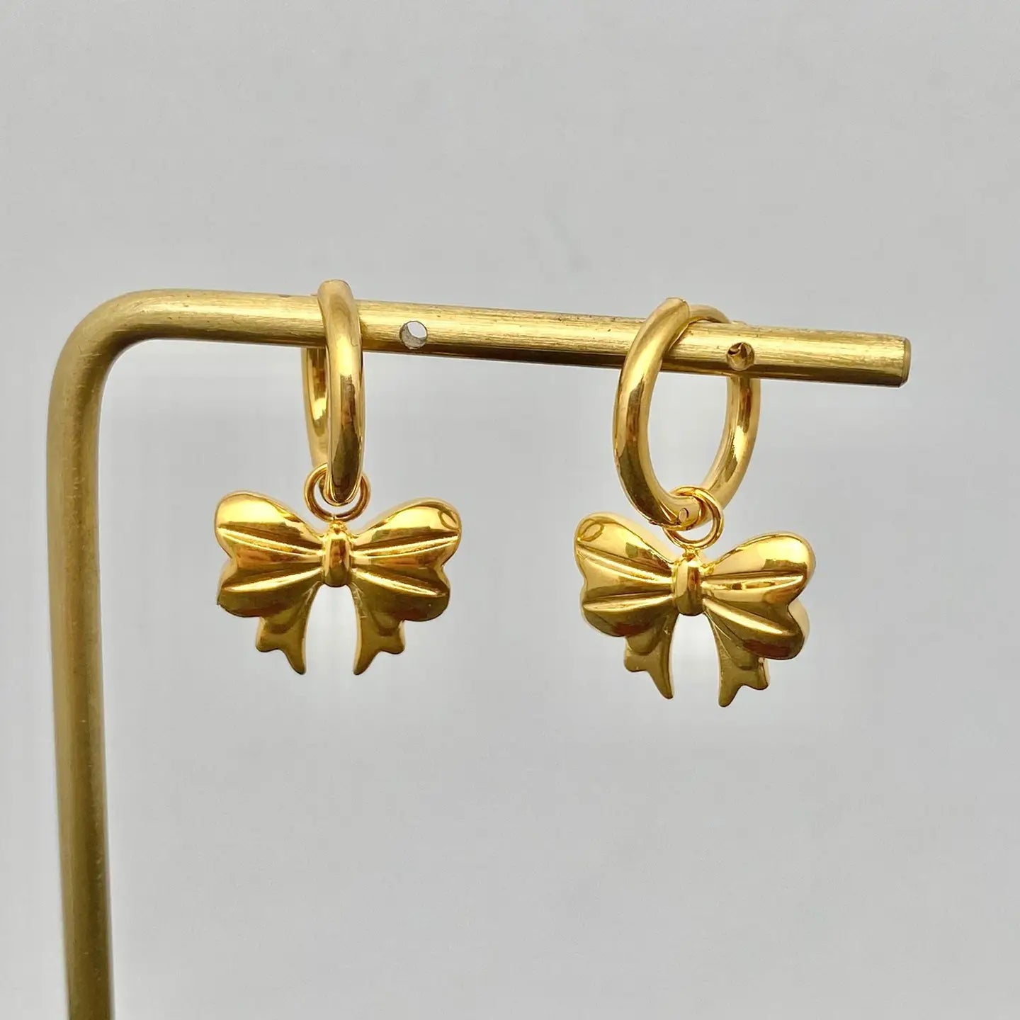 Gold bow-shaped earrings on a gray background