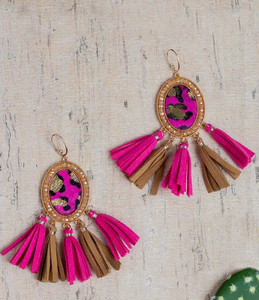 Pair of tassel earrings with pink and brown colors on a textured surface.