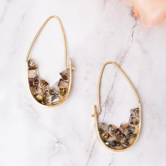 Gold hoop earrings with embedded stones on a marble surface